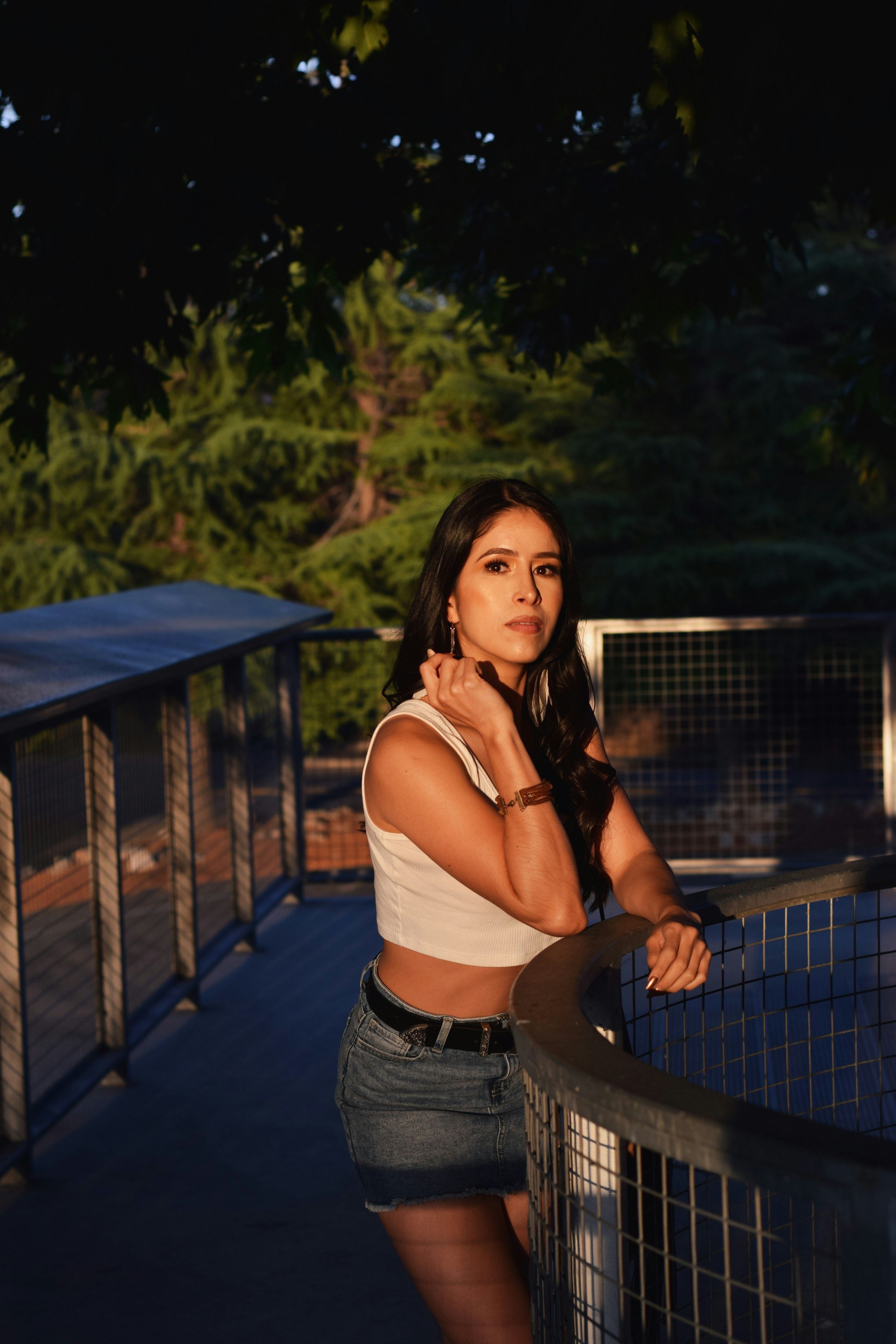 a woman leaning on a fence posing for a picture