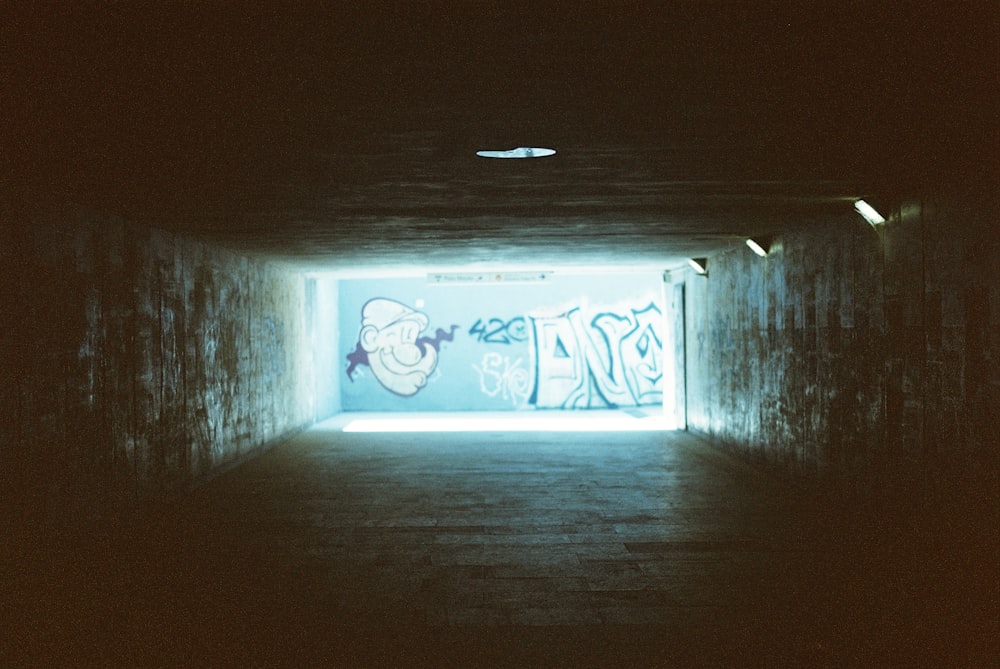 a dark tunnel with graffiti on the walls