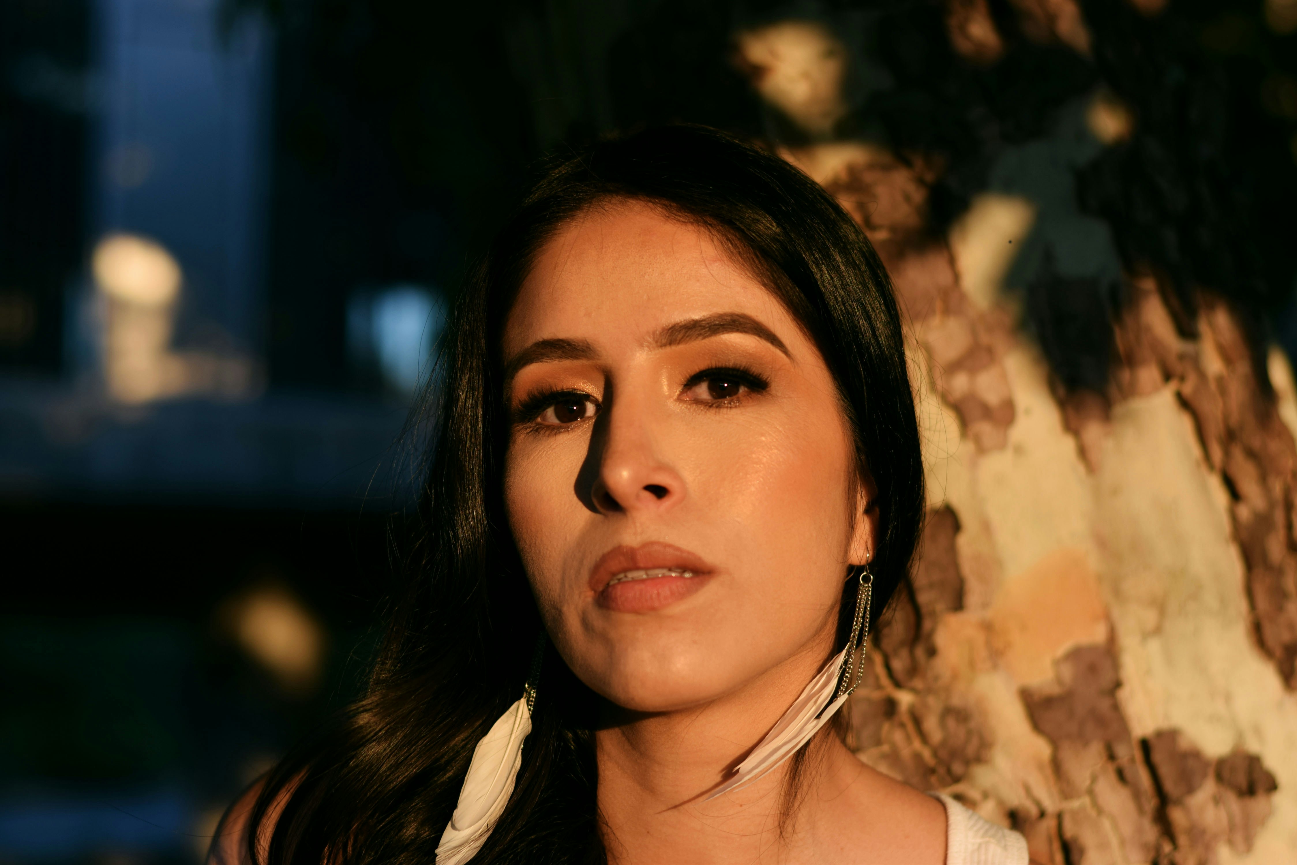a woman standing next to a tree in front of a building