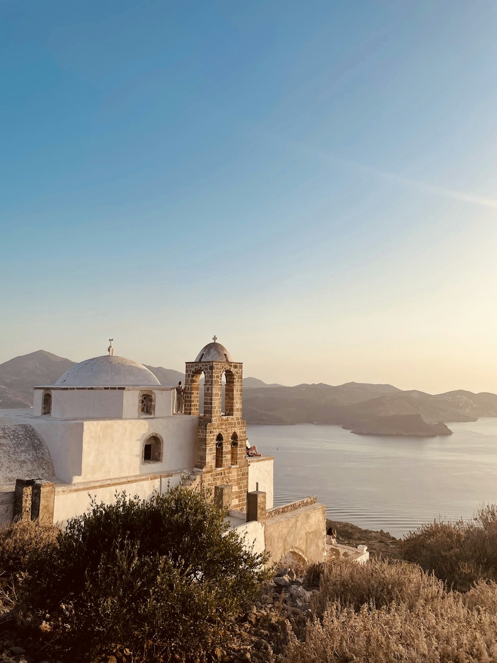 a white church on a hill overlooking a body of water