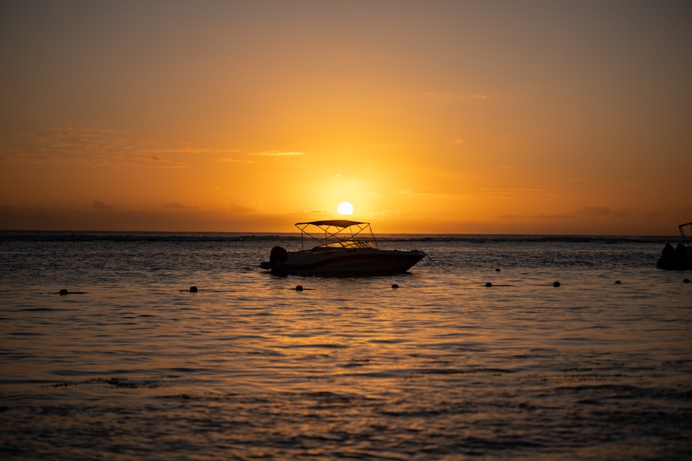 a boat floating on top of a body of water at sunset