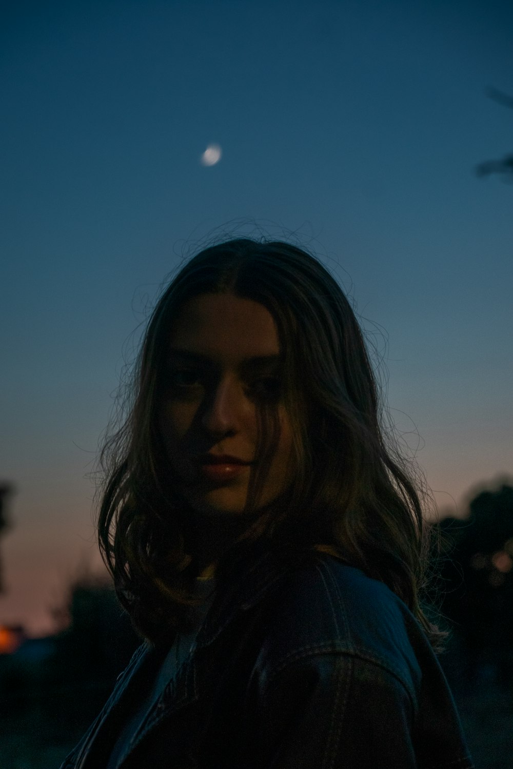 a woman standing in the dark with a moon in the background