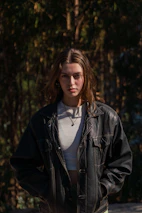 A model wearing a bohemian jacket with nature-inspired patterns standing against a backdrop of wildwoods.