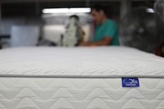 a man is working on a mattress in a warehouse
