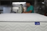 a man is working on a mattress in a warehouse