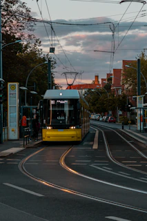 A sleek yellow and black public bus gliding through a city street at sunset, highlighting geltona linija's commitment to modern, reliable transport.