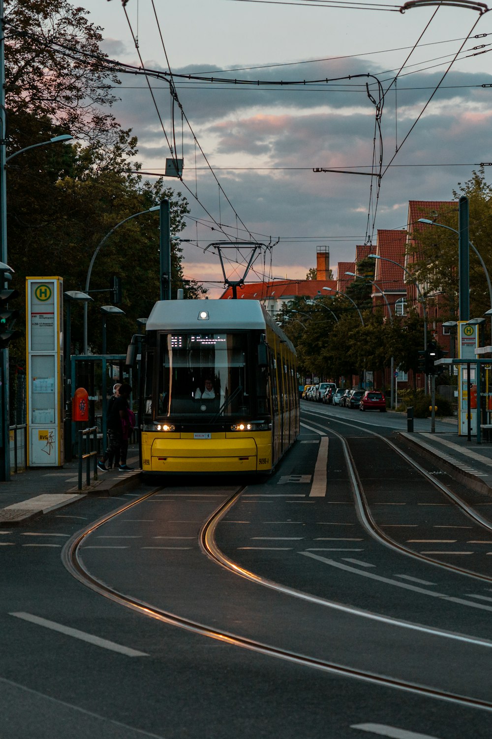 a yellow and white bus driving down a street