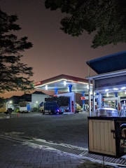 A fuel tanker truck parked at a modern fuel farm under moody evening skies.
