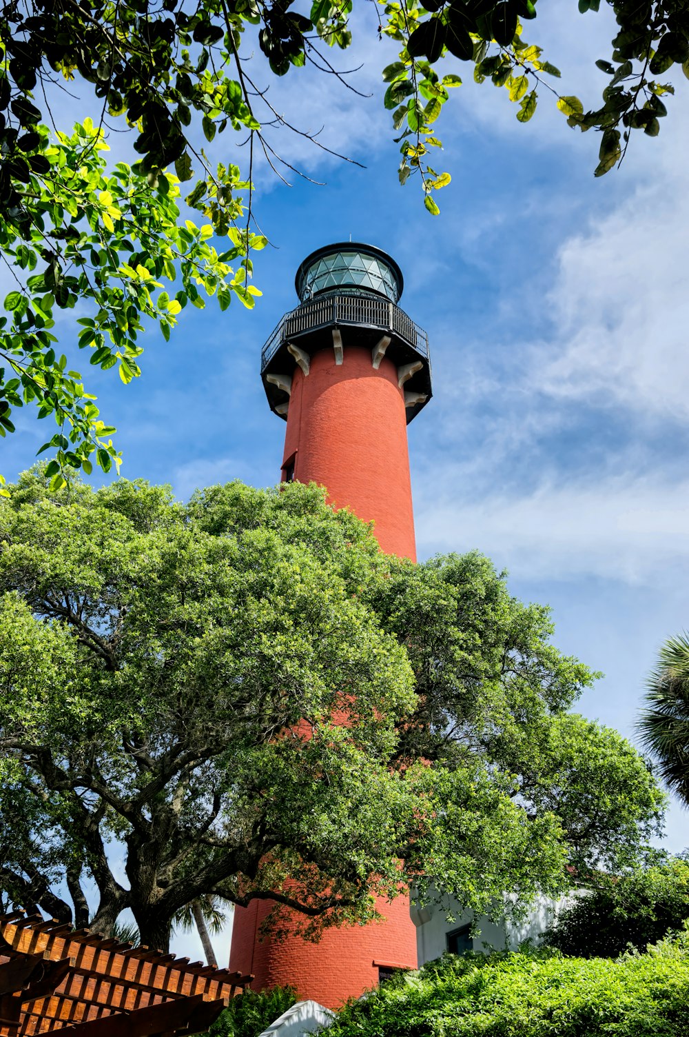 a red light house surrounded by trees and bushes