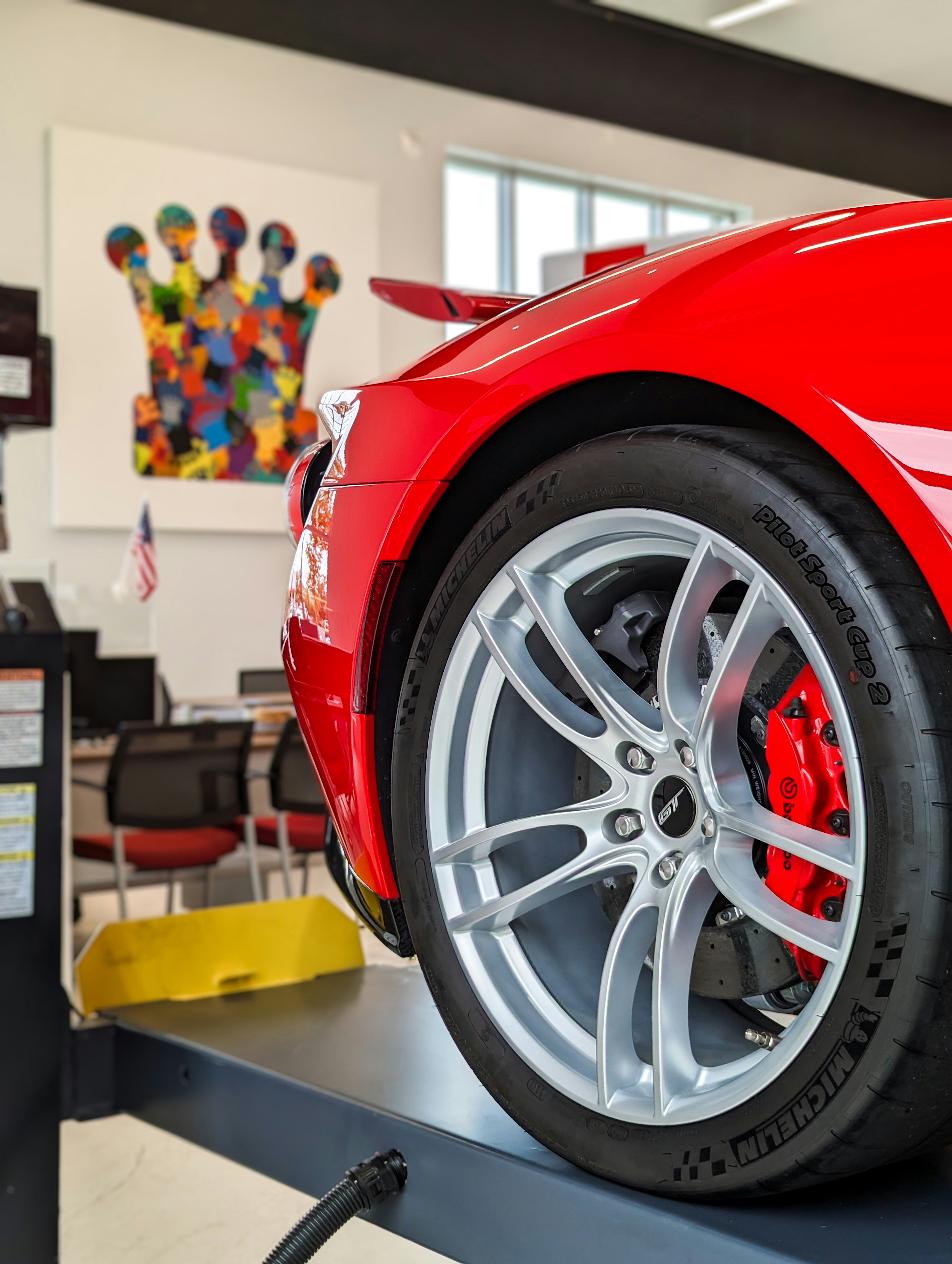 Red automotive wheel rim with glossy powder coated finish in professional workshop