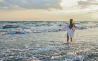 a woman standing in the water at the beach