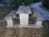 A sturdy stone picnic bench with matching stools in a garden patio.