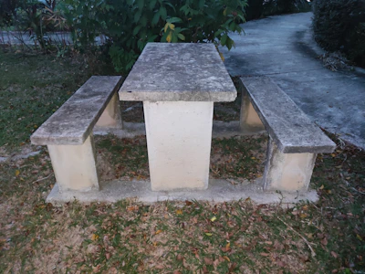 A sturdy stone picnic bench with matching stools in a garden patio.