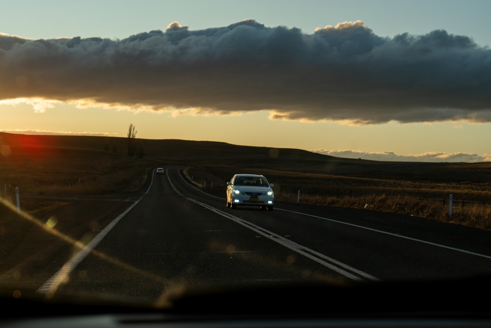 a car driving down a road under a cloudy sky