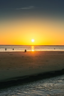 Sunset view over a serene beach with tourists enjoying the scenery.