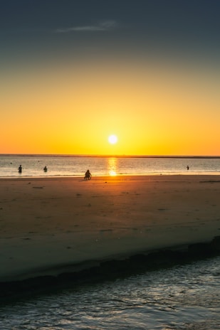 Sunset view over a serene beach with tourists enjoying the scenery.