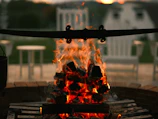 Campfire area near the tent spots with soft glowing flames and rustic seating.