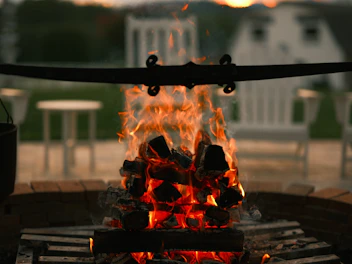 Campfire area near the tent spots with soft glowing flames and rustic seating.