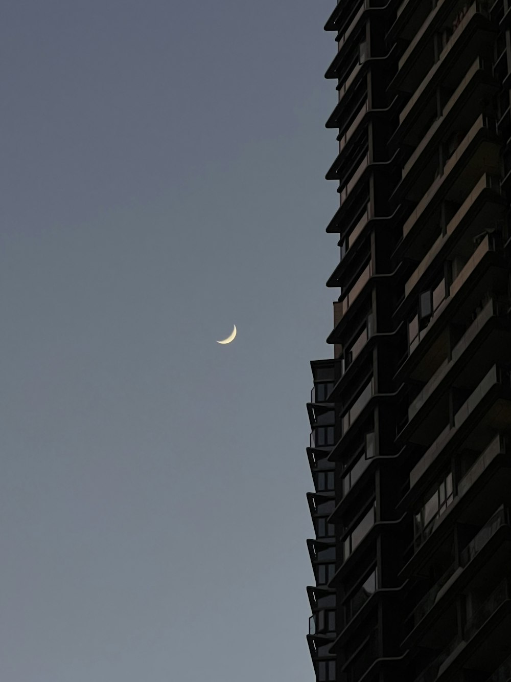 a half moon is seen in the sky between two buildings