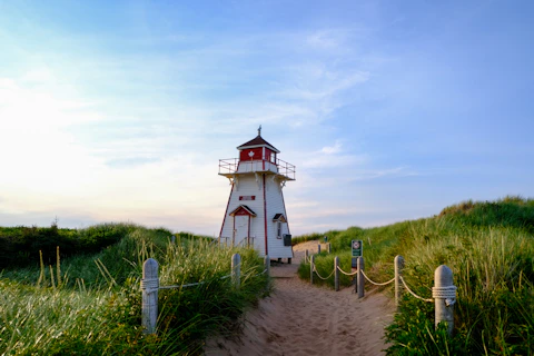 a white and red lighthouse sitting on top of a sandy beach