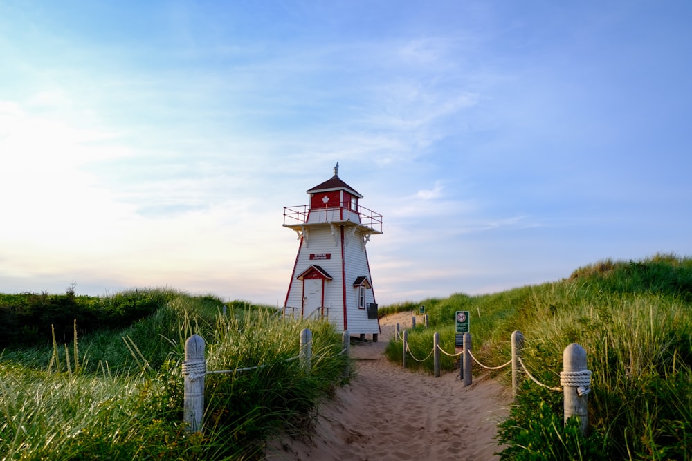 a white and red lighthouse sitting on top of a sandy beach