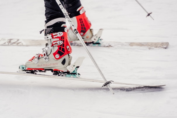 Close-up of sleek ski boots and matching gloves resting on fresh snow.