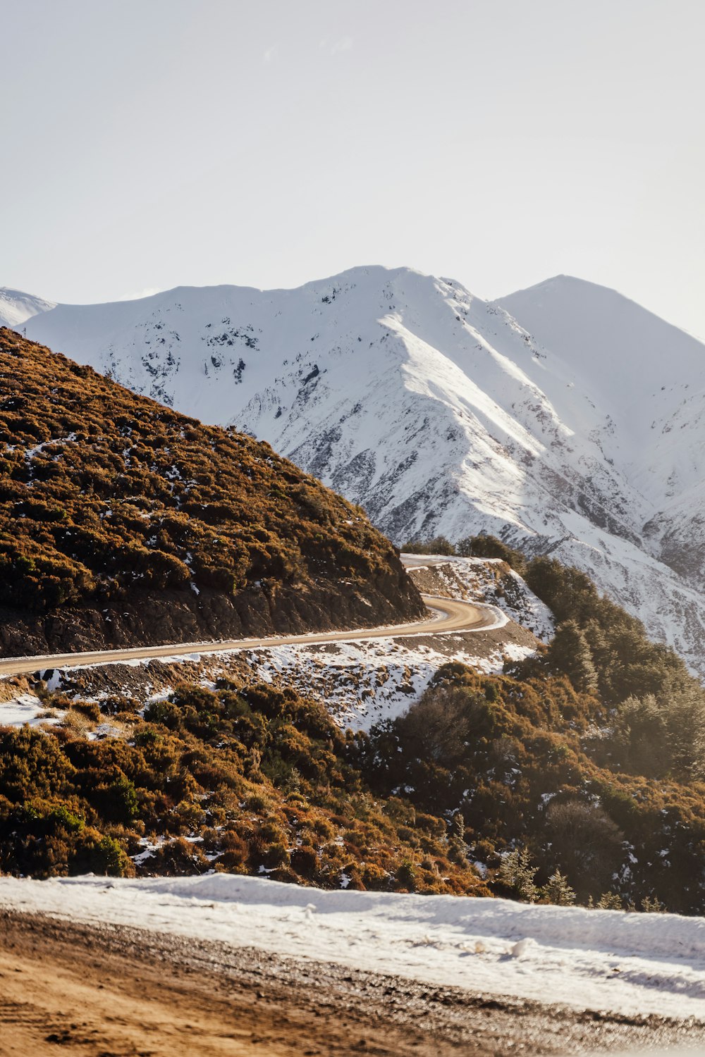 a snowy mountain with a winding road in the foreground