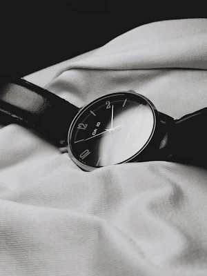 A sleek, minimalist watch resting on a soft beige fabric background.