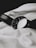 A classic analog wristwatch with a dark leather strap lies on a textured white fabric. The watch face is black with minimalist numbering, reflecting a simple yet elegant design.