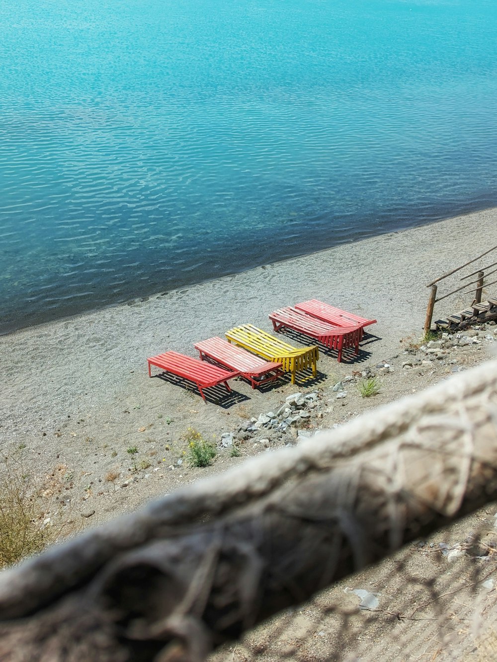 a group of red and yellow benches sitting on top of a sandy beach