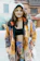 A cheerful young woman wearing a colorful oversized jacket inspired by 70s fashion.