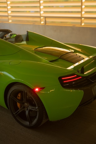 A sleek black car with a fresh lime green respray gleaming under the sunlight.