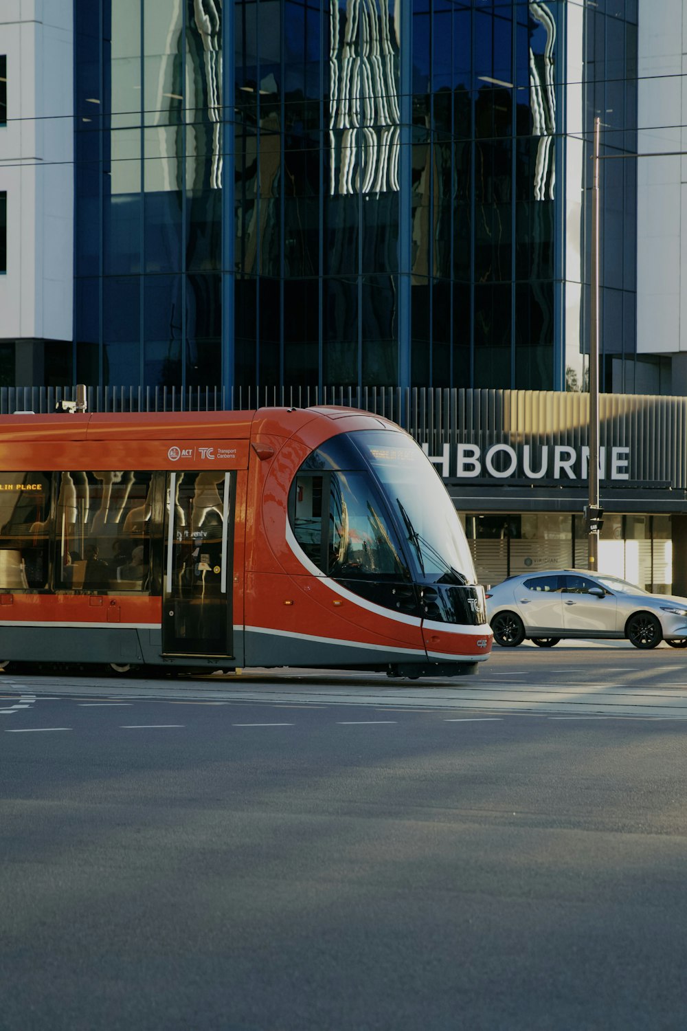 a red and white train traveling past a tall building