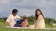 Parents and kids enjoying a picnic in a sunny park filled with wildflowers.
