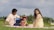 A family enjoying a picnic in a sunny park, surrounded by trees and a blanket filled with food.