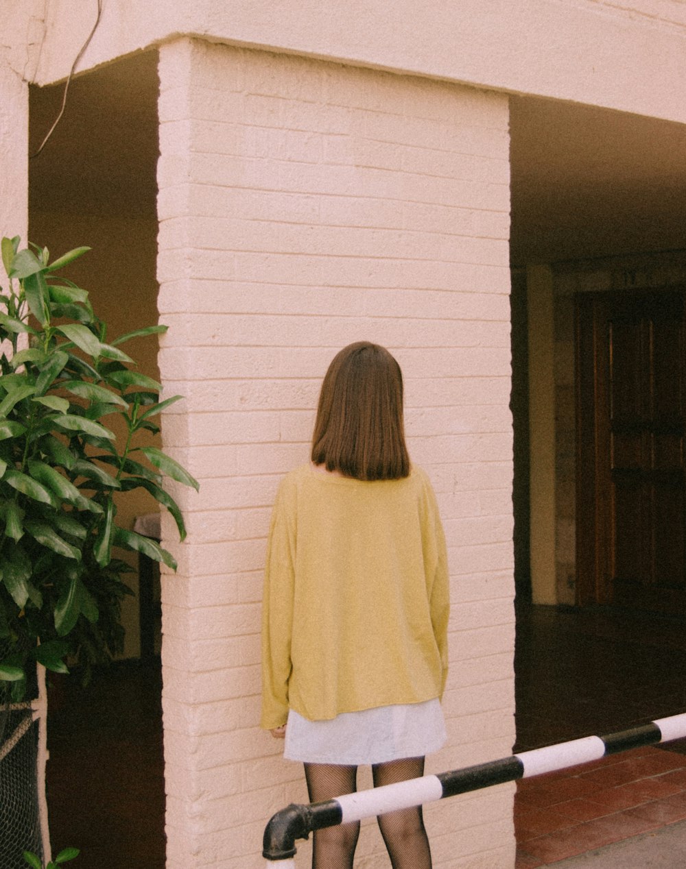 a woman standing in front of a white brick building