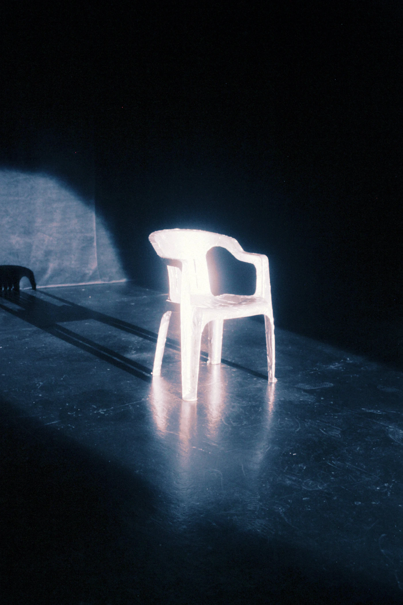 A single white chair in the middle of a dark room