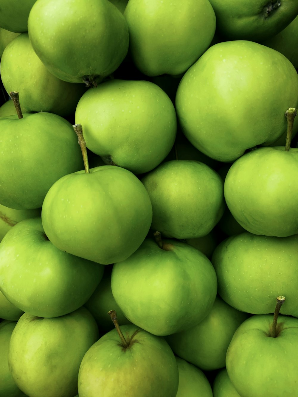 a pile of green apples sitting on top of each other