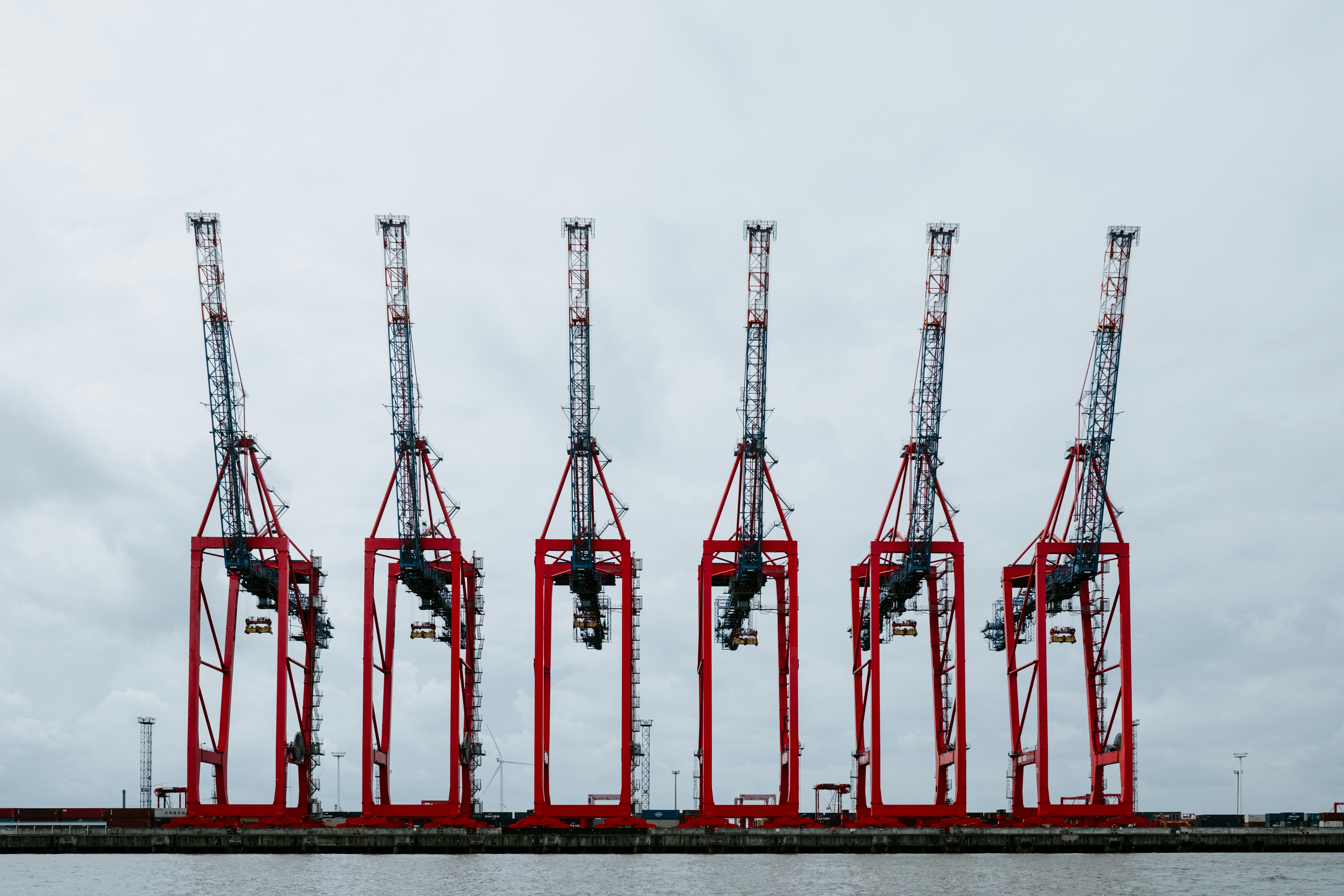 a row of red cranes sitting on top of a body of water