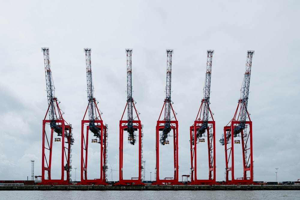 a row of red cranes sitting on top of a body of water