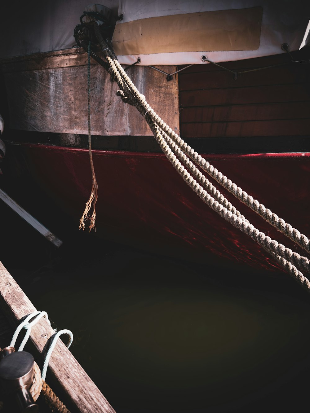 a red boat tied up to a wooden dock