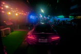 A sleek electric vehicle gliding through a neon-lit urban street at dusk.