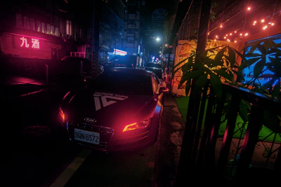 A modern Asian sedan showcased in a bustling city street illuminated by neon lights.