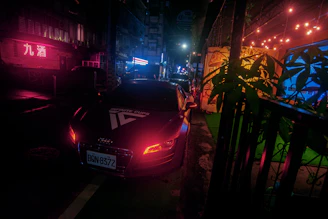 A modern Asian sedan showcased in a bustling city street illuminated by neon lights.