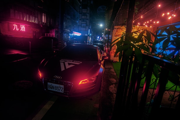 A sleek green and black hybrid car parked under the neon lights of Las Vegas at night.