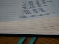 Close-up of hands flipping through the pages of 'El Convenio' with a green and gold bookmark.