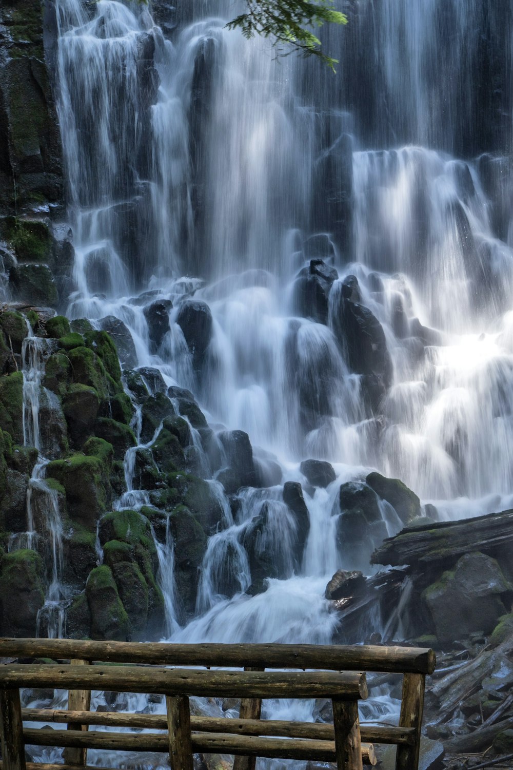 a wooden bench sitting in front of a waterfall