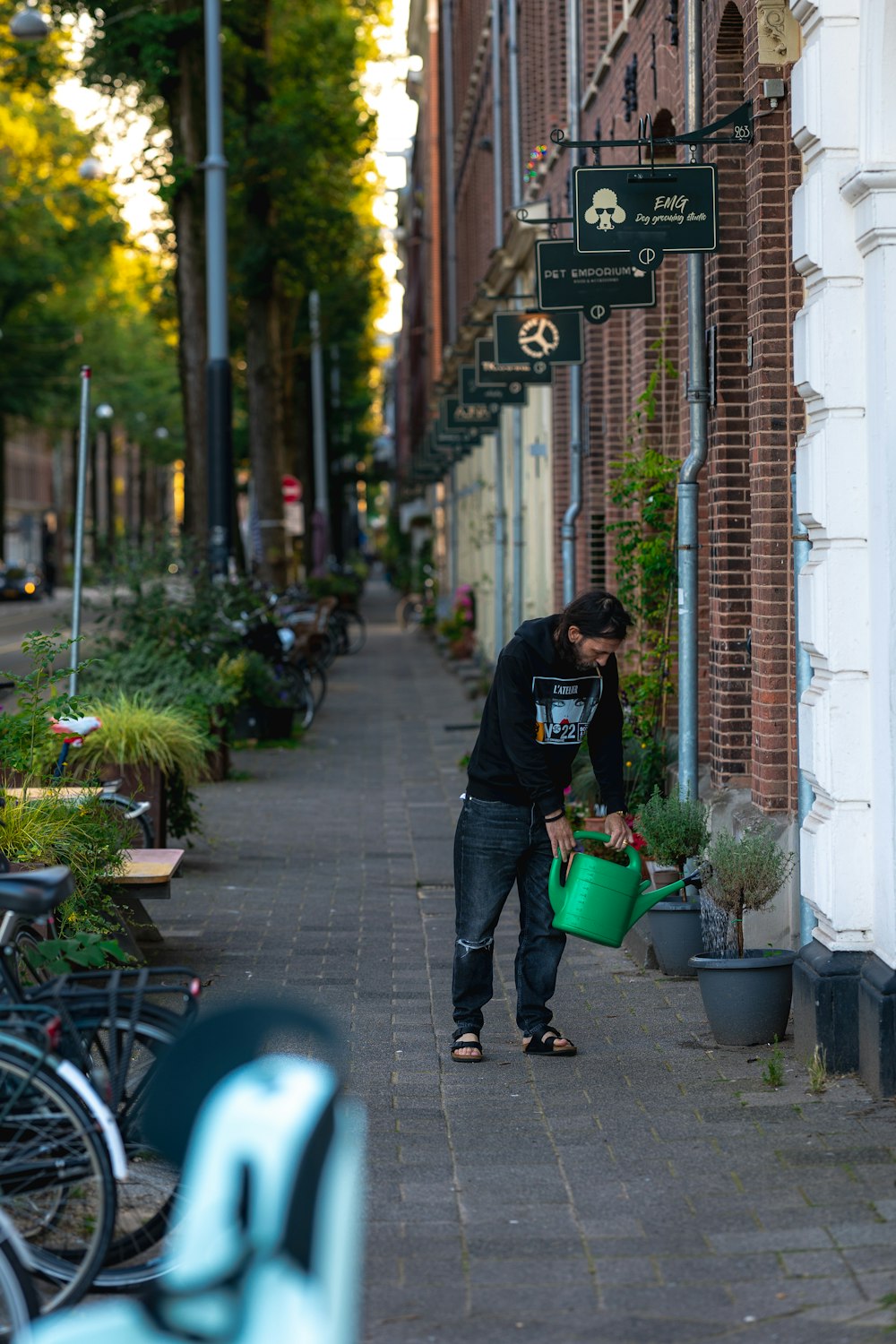 a man holding a green watering can on a sidewalk