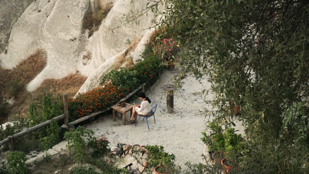 a man sitting at a table in the middle of a garden