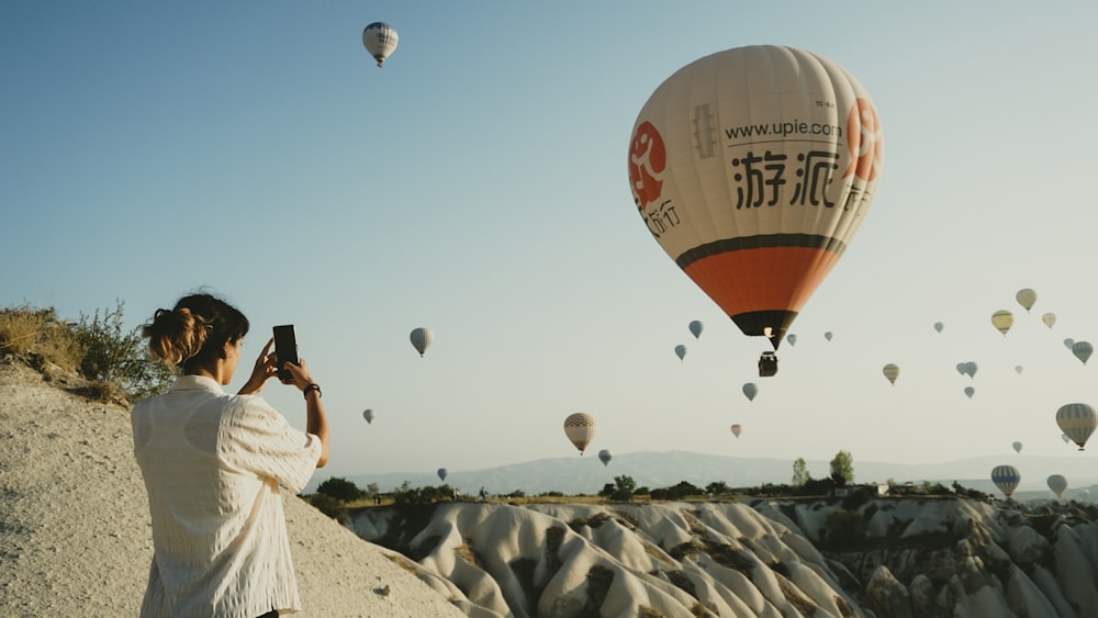 a woman taking a picture of hot air balloons